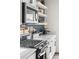 Kitchen with a modern gas range, open shelves, and blue tile backsplash at Reunion Freunion F Mobile St, Commerce City, CO 80022