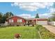 Quaint single-story home with a green lawn, vibrant flowerbeds, charming stone details, and tidy, green shrubbery at 14791 E Security Pl, Aurora, CO 80011