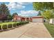 Landscaped front yard view showcasing the home's red exterior, extended driveway, and decorative shrubbery at 14791 E Security Pl, Aurora, CO 80011