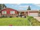 Charming red single-story home featuring a well-manicured lawn, stone accents, and a decorative water fountain at 14791 E Security Pl, Aurora, CO 80011
