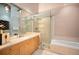 Bright bathroom features a glass shower, tub, light wood cabinets, and a wide mirror at 1720 Wazee St # 3B, Denver, CO 80202