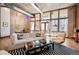 Open-concept living room with concrete wall, hardwood floors, large windows and comfortable seating at 1720 Wazee St # 3B, Denver, CO 80202