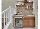 Wet bar area off basement stairs with granite countertops, wine fridge, and open shelving at 10882 Bullock Ct, Parker, CO 80134