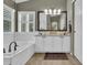 Stylish bathroom with double sinks, a large mirror, white cabinets, and a separate tub at 10882 Bullock Ct, Parker, CO 80134