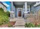 Inviting front porch with stone pillars and a stained wood door, framed by lush landscaping at 10882 Bullock Ct, Parker, CO 80134