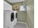 Bright laundry room features side-by-side washer and dryer, white cabinets, and a small window at 10882 Bullock Ct, Parker, CO 80134