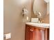 Chic powder room features wood vanity, curved sink, round mirror, and decorative towel rack at 10882 Bullock Ct, Parker, CO 80134