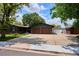 Home featuring a spacious driveway, green siding, brick accents and mature trees at 850 Idalia Cir, Aurora, CO 80011