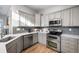 A modern kitchen features stainless steel appliances, light gray cabinets, and quartz countertops at 12071 S Tallkid Ct, Parker, CO 80138