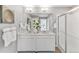 Modern bathroom featuring double sinks, white cabinetry, and a glass-enclosed shower at 1884 Westport Ave, Berthoud, CO 80513