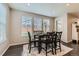 Bright dining area with dark wood table, matching chairs, and natural light from three large windows at 14067 Hudson St, Thornton, CO 80602