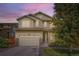 Inviting two-story home with a manicured lawn, charming front porch, and attached two-car garage at dusk at 14067 Hudson St, Thornton, CO 80602