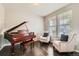 Living room with a dark hardwood floor, a piano and two chairs with black and white pillows at 14067 Hudson St, Thornton, CO 80602
