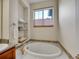 Bright bathroom featuring a soaking tub beneath a window and built in shelves for towels at 9085 E Phillips Dr, Centennial, CO 80112