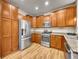 Spacious kitchen featuring stainless steel appliances, wooden cabinets, granite countertops, and wood flooring at 9085 E Phillips Dr, Centennial, CO 80112