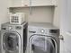 Laundry room featuring stacked front-load washer and dryer with a shelf above, optimizing space efficiency at 9085 E Phillips Dr, Centennial, CO 80112