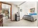 Well-lit basement bedroom with a mini fridge, window, carpet, and view of exterior entrance through a door at 6252 King Dr, Evergreen, CO 80439
