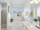 Bright bathroom features a soaking tub, tiled shower, vanity with sink, and large window at 1913 Julian St, Denver, CO 80204