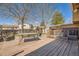 Backyard deck with wooden bench, table and fence surrounded by mature trees and clear skies overhead at 4593 S Field St, Littleton, CO 80123