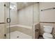 Tile bathroom with a glass enclosed shower featuring built in bench and toilet at 2485 Vale Way, Erie, CO 80516