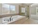 Bright bathroom featuring a soaking tub, glass shower, and tiled flooring at 2485 Vale Way, Erie, CO 80516