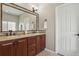 Bathroom featuring a double vanity with a dark wood cabinet, a large mirror, and neutral tiling at 2485 Vale Way, Erie, CO 80516