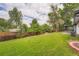 Sprawling backyard with lush green grass, mature trees, wood fence, and patio area for outdoor entertaining at 1819 S Nile Ct, Aurora, CO 80012