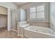 Bright bathroom featuring a shower with glass doors, a soaking tub, and natural light from a window at 8107 S Catawba Ct, Aurora, CO 80016