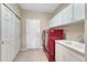 Bright laundry room with a sleek red washer and dryer, and ample cabinet space at 8107 S Catawba Ct, Aurora, CO 80016