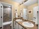 Well-lit bathroom with a double sink vanity, tiled countertop, and walk-in shower with designer tile at 6266 W Prentice Ave, Littleton, CO 80123