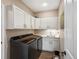 Well-organized laundry room with gray washer/dryer, white cabinetry, sink, and stylish wood-look tile floors at 6266 W Prentice Ave, Littleton, CO 80123