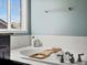 Close up of soaking tub and tile surround with tub caddy and bright window at 10730 Hillrose St, Parker, CO 80134