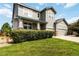 Beautiful home featuring a lush green lawn, manicured bushes, gray siding, and a welcoming front porch at 10730 Hillrose St, Parker, CO 80134