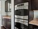 Modern kitchen features stainless steel double ovens and dark wood cabinets at 10730 Hillrose St, Parker, CO 80134
