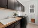Bright laundry room with a sleek black washer, wood countertop, and ample cabinet space at 10730 Hillrose St, Parker, CO 80134
