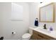 Well-lit powder room with wooden vanity, white sink, modern faucet, and window at 4485 E Andover Ave, Castle Rock, CO 80104