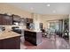 Open kitchen with an island, dark wood cabinets, granite countertops, stainless appliances, and adjacent dining area at 6267 N Dunkirk Ct, Aurora, CO 80019