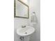 Small bathroom with pedestal sink and decorative mirror at 9044 W 63Rd Ave, Arvada, CO 80004