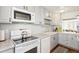 Well-lit kitchen with white cabinets, modern appliances, a view into the living room, and laminate countertops at 9044 W 63Rd Ave, Arvada, CO 80004