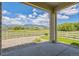 Covered back patio with scenic view, featuring a concrete patio and white fence overlooking green space at 1842 Peak Prairie Ln, Monument, CO 80132