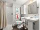Bathroom featuring a shower with white subway tile, a pedestal sink, toilet, modern decorations, and dark tile floors at 4250 Wyandot St, Denver, CO 80211