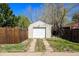 Single car garage with a white door, surrounded by a wooden fence and foliage at 3492 S Elm St, Denver, CO 80222