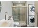 Modern bathroom featuring a glass enclosed shower and convenient laundry area with stacked washer and dryer at 2658 S Xanadu Way # B, Aurora, CO 80014