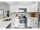 Kitchen featuring white cabinets, quartz countertops, stainless steel appliances, and stylish backsplash at 2658 S Xanadu Way # B, Aurora, CO 80014