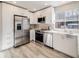 Bright kitchen features stainless steel appliances, white cabinets, and light wood-look floors at 717 Walden Ct, Highlands Ranch, CO 80126