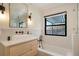 Bright bathroom featuring light wood vanity, black fixtures, soaking tub, and window at 4895 E Arizona Ave, Denver, CO 80246