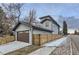 Modern home featuring a gray exterior, a brown garage door and a wooden fence at 2540 Xavier St, Denver, CO 80212