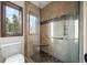 Bathroom shower and toilet area featuring mosaic tile flooring, glass shower door, and a window at 33379 Buffalo Park Rd, Evergreen, CO 80439