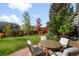 Inviting backyard patio featuring an outdoor dining table and chairs, surrounded by mature trees and landscaping at 6143 Eldora St, Golden, CO 80403