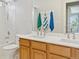 Bathroom with double sinks, wooden vanity, a shower and tub combination, and hanging colorful towels at 10570 Humboldt Peak Way, Parker, CO 80138